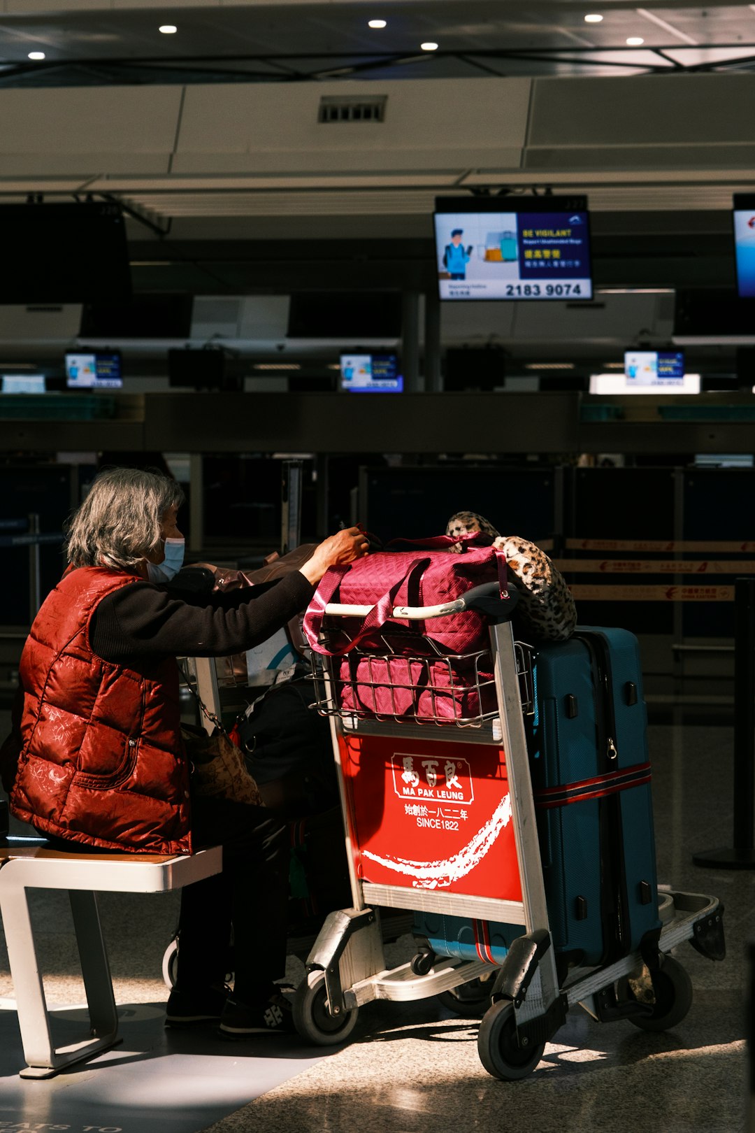 a woman sitting in a chair next to a luggage cart