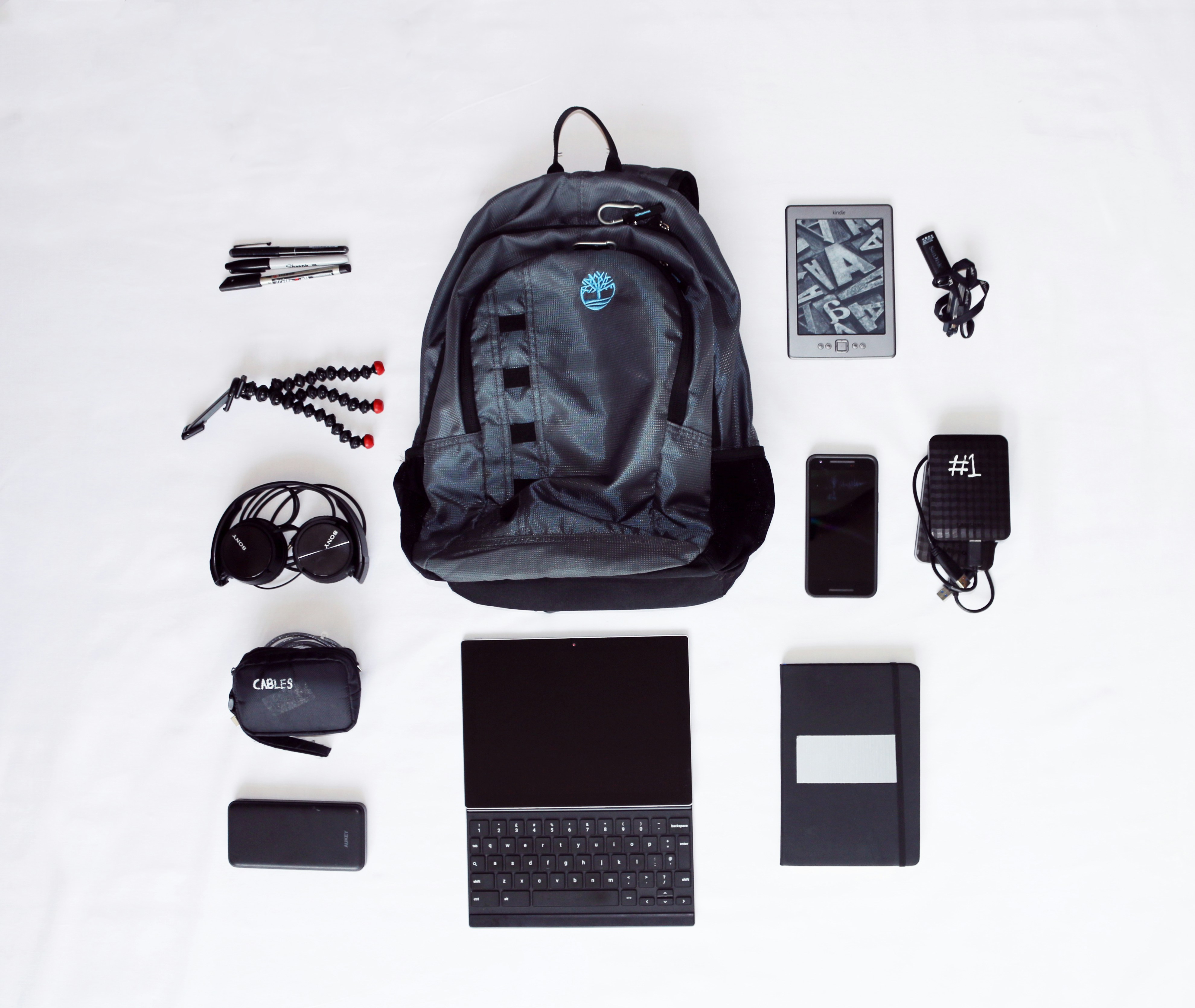 flat lay photography of backpack, laptop computer, headphones, smartphone, and octopus tripod